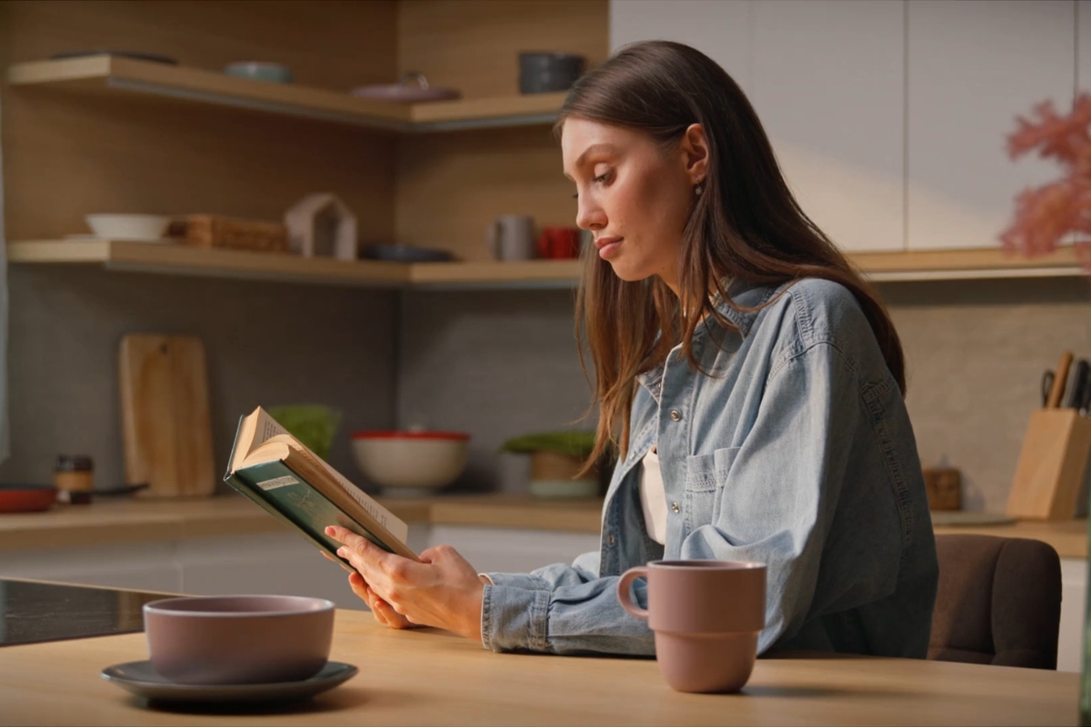 devojka čita knjigu u svom domu i pije kafu
