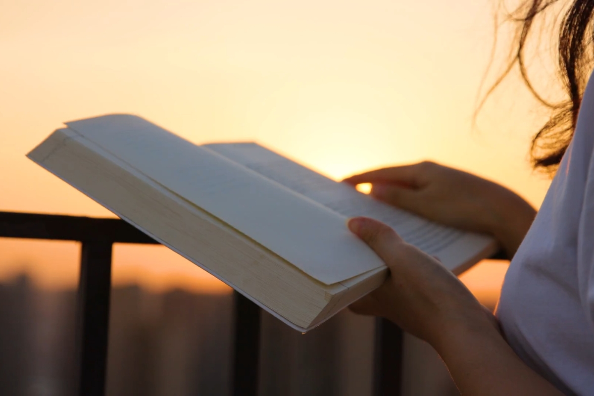 devojka čita knjigu na zalasku sunca